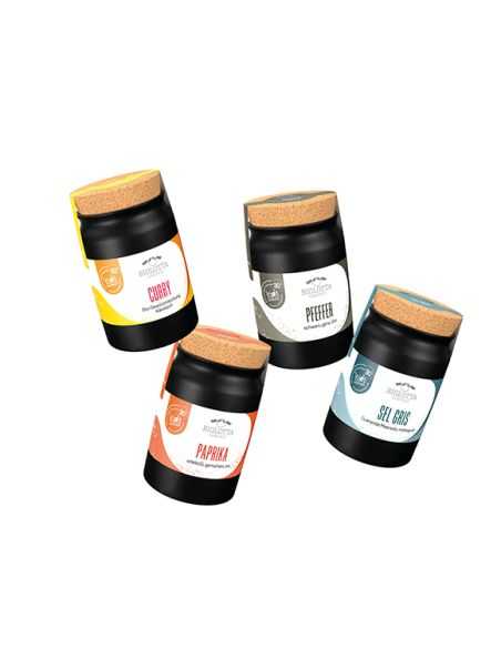 Vier schwarze Keramiktöpfchen mit unterschiedlich farbigen Etiketten, aufrecht und schräg nebeneinander platziert.