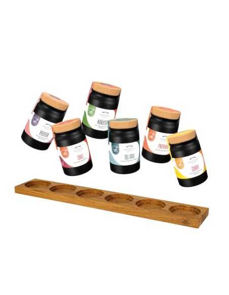 Sechs schwarze Keramiktöpfchen mit verschiedenfarbigen Etiketten über einem länglichen Holzhalter mit sechs runden Vertiefungen.