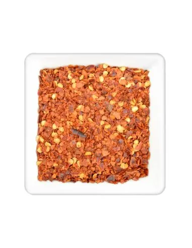 Geschrotete rote Chiliflocken mit gelben Samen in weißer Schale.