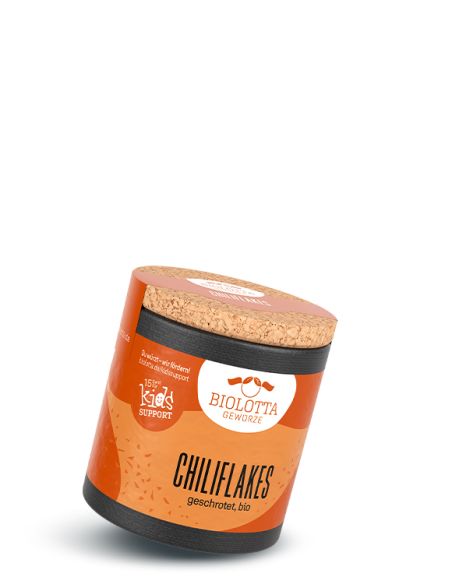 Gelb-orangefarbene Pappdose mit dem Etikett Chiliflakes, leicht schräg liegend, mit Korkdeckel und schwarzem Bodenband.