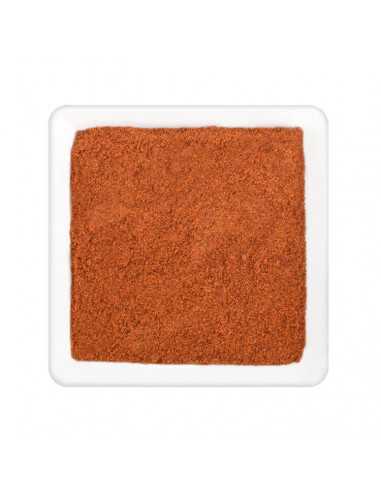 Feines, rötlich-orangenes Paprikapulver gleichmäßig verteilt in einer weißen quadratischen Schale.