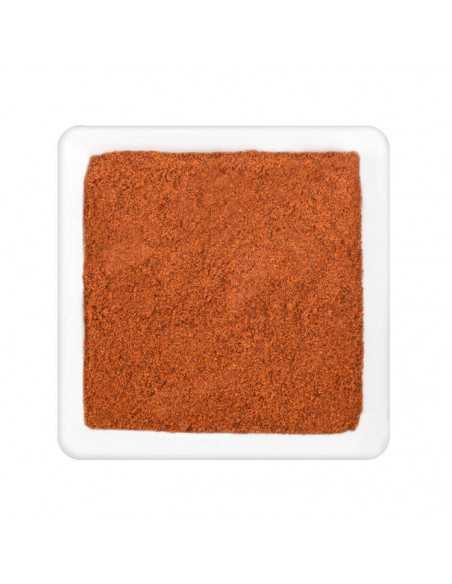 Feines, rötlich-orangenes Paprikapulver gleichmäßig verteilt in einer weißen quadratischen Schale.