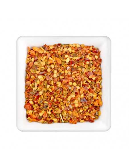 Weiße Schale mit einer bunten Mischung aus grob gehackten roten und gelben Chilistückchen und Kernen.