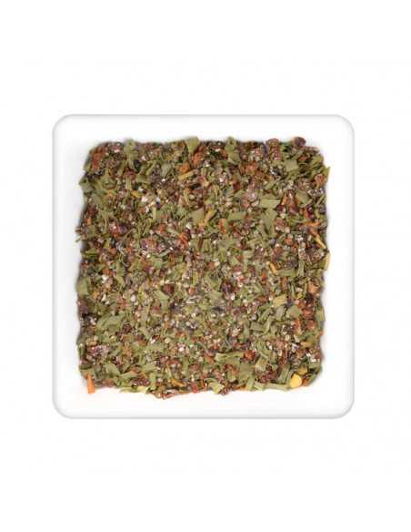 Quadratischer Teller mit grober Kräutermischung aus grünen Blättern, roten Stückchen und Gewürzgranulat