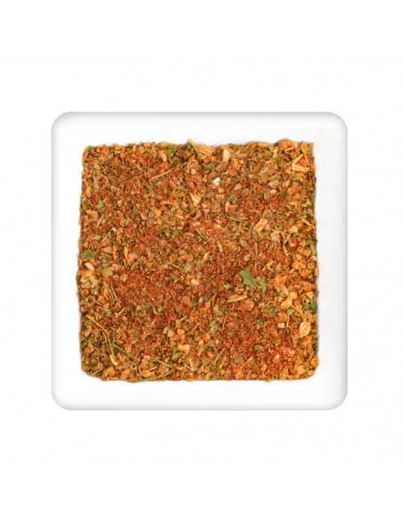 Quadratischer Teller mit grober, rot-grüner Gewürzmischung aus Kräuterstückchen und Paprikapulver