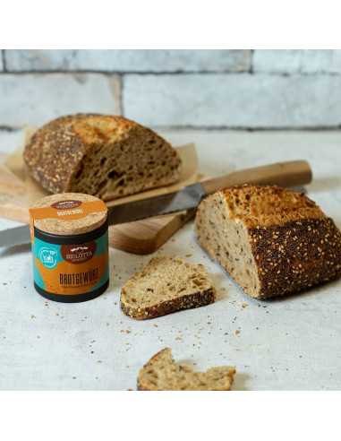 Angeschnittenes Brot mit Brotscheiben, Brotmesser und passender Pappdose auf hellem Untergrund