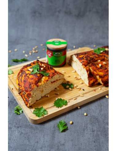 Schwarze Pappdose neben aufgeschnittenem Pizzabrot mit Pinienkernen und Koriander auf Holzbrett