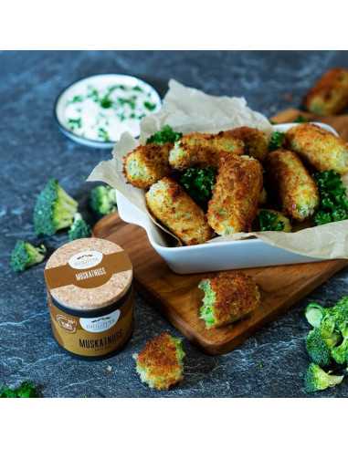 Brokkolistäbchen in einer weißen Schale mit Muskatnuss-Gewürzdose im Vordergrund.