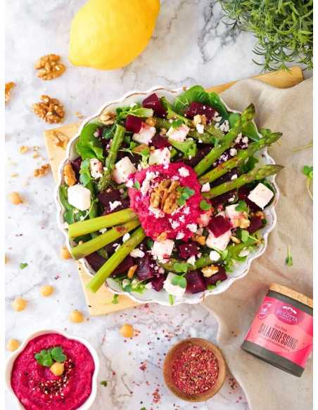 Schwarze Pappdose neben einem Salatteller mit grünem Spargel, Roter Bete, Feta und leuchtend pinkem Dressing