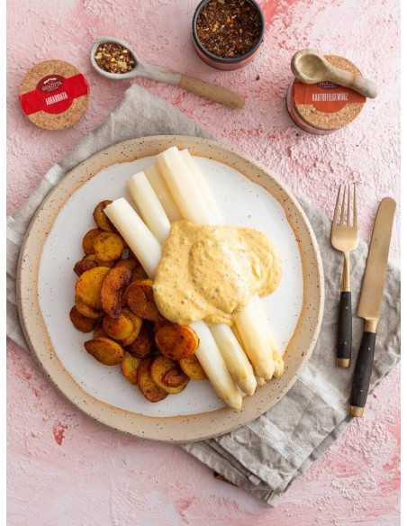 Offene Dose Arrabbiata neben Teller mit weißem Spargel, Bratkartoffeln und heller Soße, im Hintergrund weitere Gewürzdosen