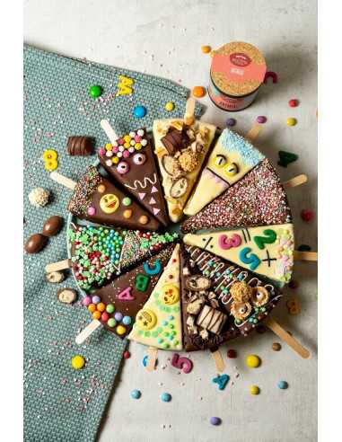 Schwarze Pappdose neben bunt dekorierten Kuchenecken mit Streuseln, Schokolade und Zahlen- oder Buchstabenmotiven