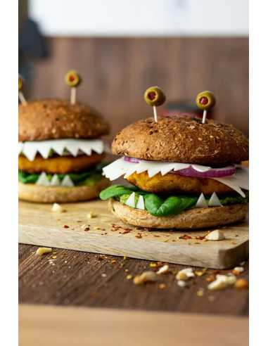 Zwei Burger mit gezacktem Käse, Spinat, Zwiebeln und Oliven auf Holzbrett.