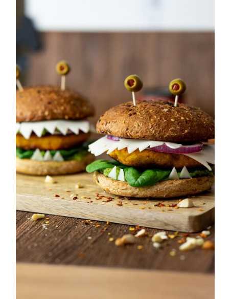 Zwei Burger mit gezacktem Käse, Spinat, Zwiebeln und Oliven auf Holzbrett.