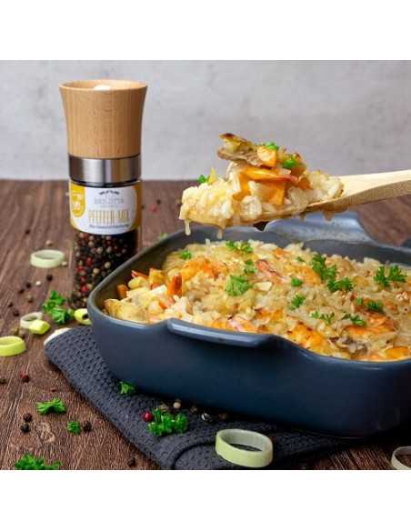 Auflaufform mit Gemüse-Reis-Gericht, darüber eine Holzlöffel-Portion; im Hintergrund eine Gewürzmühle mit gelbem Etikett. Auflaufform mit Gemüse-Reis-Gericht, darüber eine Holzlöffel-Portion; im Hintergrund eine Gewürzmühle mit gelbem Etikett.