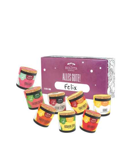 Acht bunte Bio-Pappdosen vor lilafarbener Geschenkbox mit dem Schriftzug „Alles Gute!“ und einem Namensfeld.