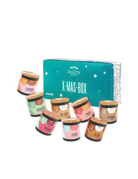 Acht bunte Bio-Pappdosen vor türkisfarbener Geschenkbox mit der Aufschrift „X-MAS-BOX“.