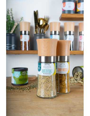 Zwei Mühlen auf dem Tisch platziert und im Hintergrund Wandregale mit Gewürzmühlen und Keramiktöpfchen platziert