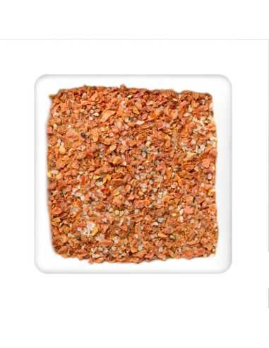 Quadratischer Teller mit grober gewürzmischung aus orangefarbenen stückchen und sichtbaren salzkristallen