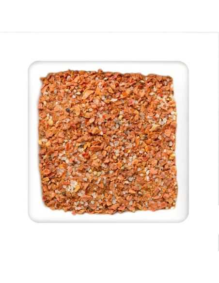 Quadratischer Teller mit grober gewürzmischung aus orangefarbenen stückchen und sichtbaren salzkristallen