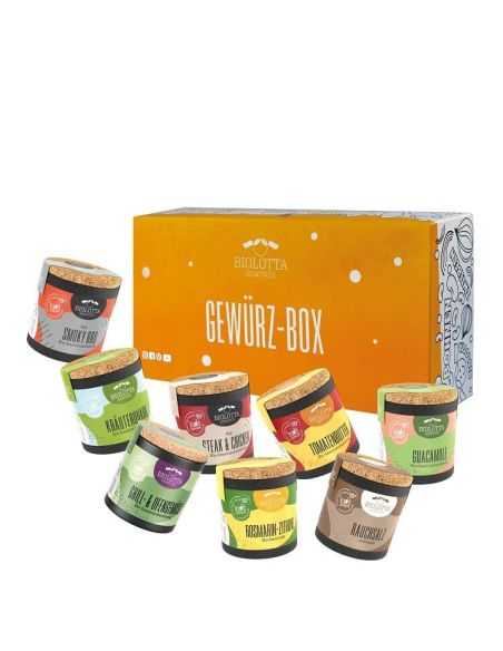Acht bunte Bio-Pappdosen vor einer orangefarbenen Geschenkbox mit der Aufschrift „Gewürz-Box“