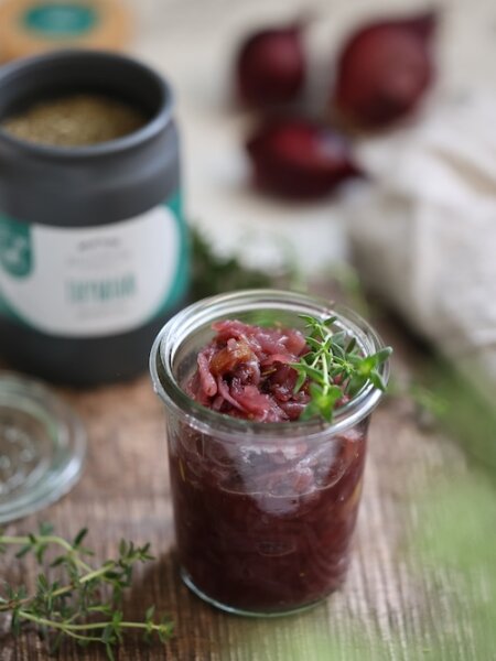 Karamellisierte Zwiebelmarmelade mit frischen Feigen, gewürzt mit BioLotta Rosmarin und Thymian, in Gläsern abgefüllt – perfekt zu Käse oder als Geschenkidee.