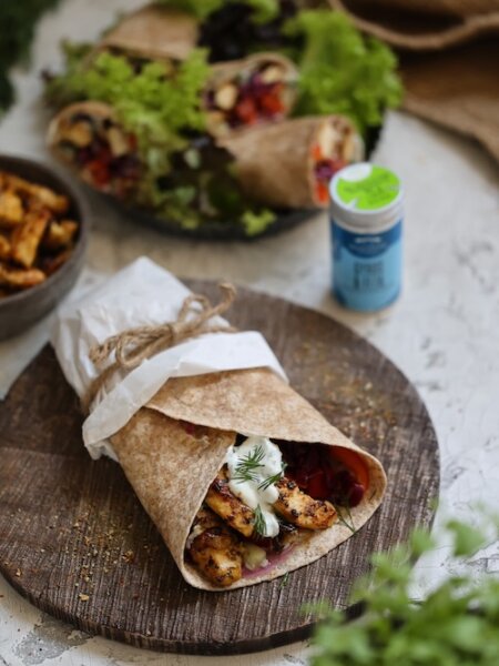 Wraps mit Gyros-Hähnchen, frischem Gemüse und Joghurtsoße, angerichtet auf einem Holzbrett – ideal für ein schnelles Mittagessen