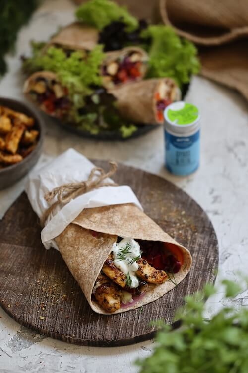Wraps mit Gyros-Hähnchen, frischem Gemüse und Joghurtsoße, angerichtet auf einem Holzbrett – ideal für ein schnelles Mittagessen